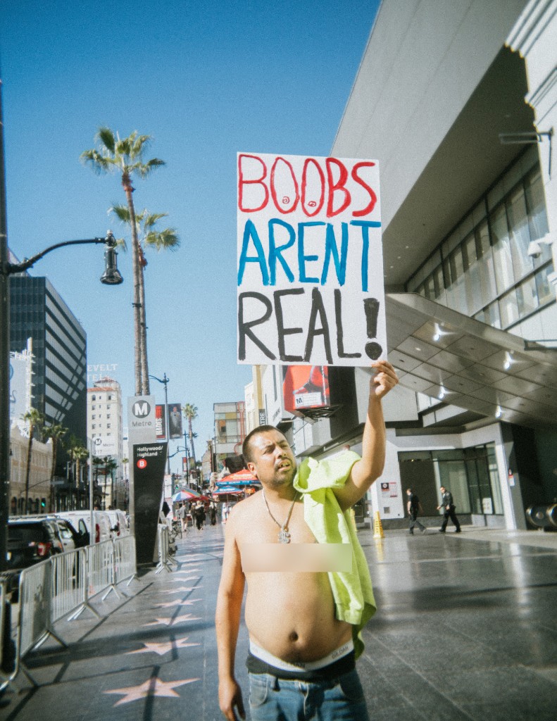 Community member holding the BOOBS AREN'T REAL sign