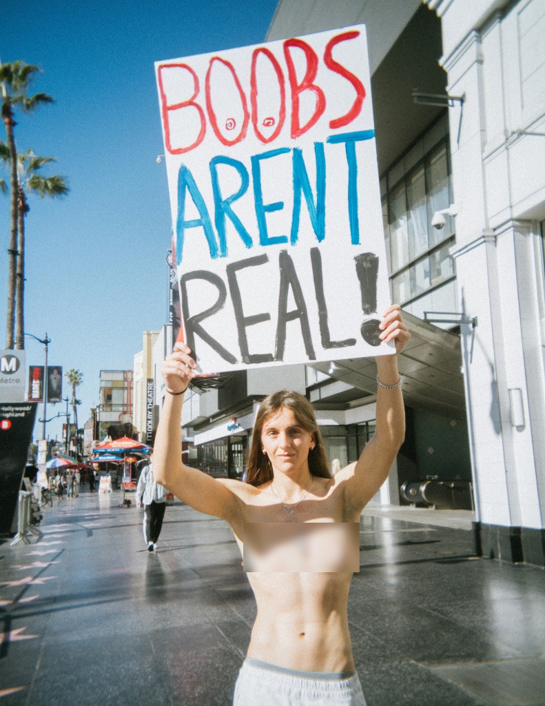 Lillian Lover holding BOOBS AREN'T REAL sign above her head on Hollywood Boulevard